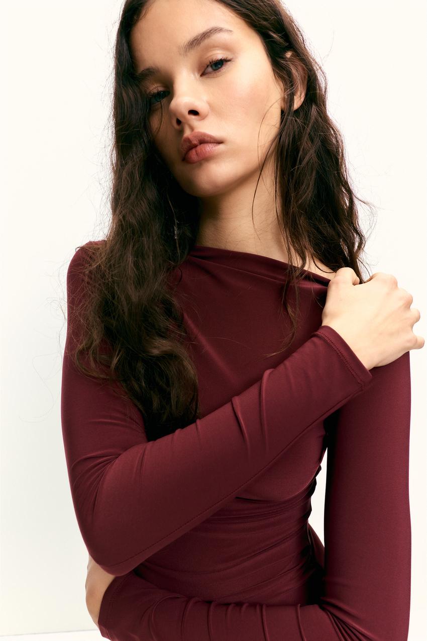 "Mid-shot of a burgundy midi dress with a draped waist detail and long sleeves."
