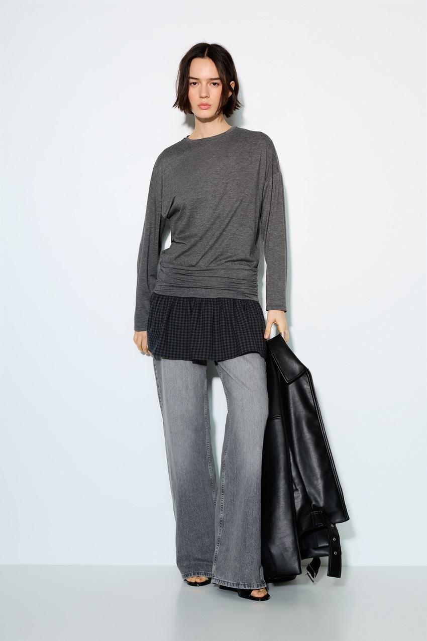 Dark grey dress set with a plain top and a checked skirt, paired with flared grey trousers.
